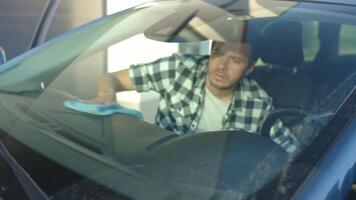 Man wiping car dashboard with microfiber cloth while sitting inside vehicle video