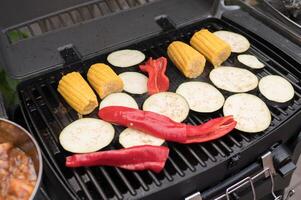 Grilled vegetables corn, eggplant, and red peppers on outdoor barbecue grill photo