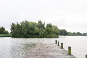 Serene lake view with wooden pier and lush green island in tranquil landscape photo