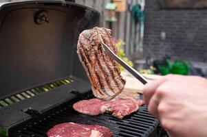 Grilling juicy steaks on barbecue grill in backyard cookout photo