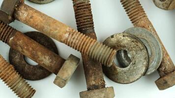 A collection of rusty bolts and nuts arranged on a white surface. The metal pieces show signs of wear and corrosion, highlighting their industrial nature. video