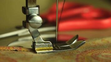 Close-up of a sewing machine foot with a needle and thread. Scissors are visible in the background. video