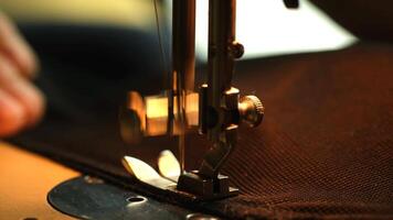 Close-up of a sewing machine needle stitching fabric. The machine is metallic with a thread passing through the needle, focused on the sewing process. video