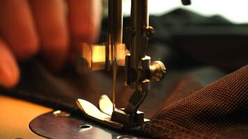 Close-up of a sewing machine in action. A hand guides fabric under the needle. The scene highlights the art of sewing and craftsmanship. video