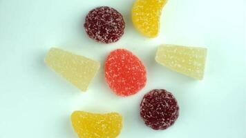 Colorful gummy candies arranged in a circular pattern on a white background. The candies are various shapes and vibrant colors, including red, yellow, and orange. video