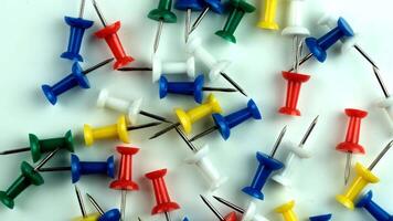 Colorful push pins scattered on a white surface. Various colors include red, blue, green, yellow, and white. Ideal for office or school use. video
