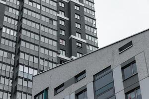 Architecture of tall modern apartment building. Urban highrise facade with geometric glass windows, photo