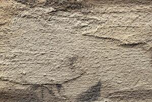 Golden textured wall with rough, grungy surface and antique pattern. Aged, weathered metal or stone photo