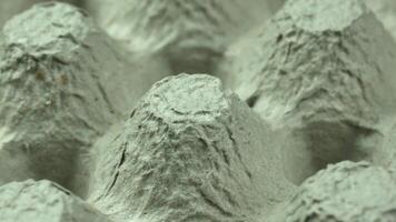 Close-up of an egg carton with a textured gray background. The carton features multiple raised sections designed to hold eggs securely. video