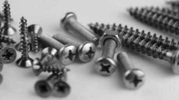 Close-up of metal screws arranged in a row. The screws have a shiny finish and visible threading. The background is blurred, emphasizing the screws. video
