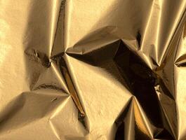 Gold foil background with crinkled texture. Wrinkled, creased, and crumpled tinfoil material photo