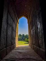 Stone arch window opening to a peaceful garden. Framed view of green nature, trees, and soft grass, photo