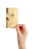 Female hand holding gold textured card with shiny foil surface and elegant shimmer. Minimalist photo