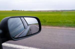 A car side view mirror is seen on the road photo