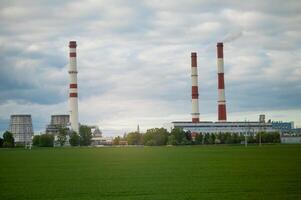A large factory with two chimneys and smoke stacks photo