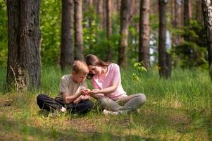 mother and son are sitting side by side in a forest photo