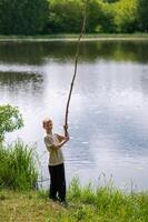 A boy holding a long stick in the grass photo