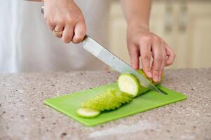 A person cutting up a green apple on a cutting board photo