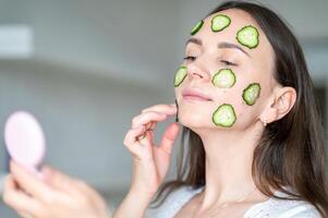 A woman applying cucumber slices to her face photo