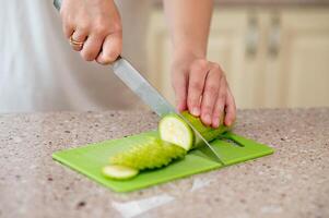 A person cutting a cucumber on a green cutting board photo