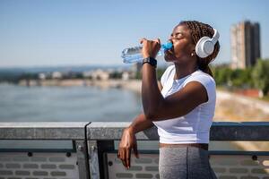 Female athlete taking a break from jogging with a bottle of water. photo