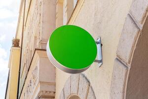 Round green signboard mockup on stone wall in bright daylight, perfect for branding, identity, logo or storefront promotion photo