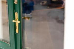Golden door handle on green frame with glass reflection, ideal for design elements, access visuals, and architectural or security themed content. photo