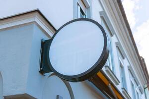 Round blank signage mounted on building facade, ideal for branding, business mockups, or commercial storefront design presentations in urban settings photo