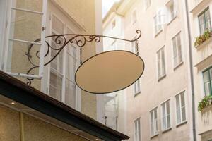 Retro style empty signage board with wrought iron support, ideal for traditional business mockups, bakery or local artisan shop branding. photo