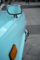Close-up of car detail, Side view mirrors on vintage convertible in bright turquoise color. Mirror is located on the hood of the car. vintage car and nostalgia concept. vertical photo