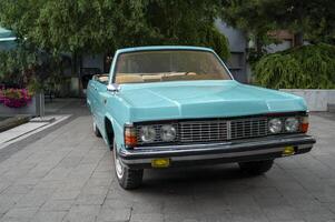 Vintage convertible, turquoise color and beige seats. stands on the street, Front view of a vintage turquoise open convertible. concept of bright summer and relaxation photo
