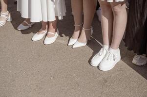 Women's legs in white shoes stand in a row. Close-up of legs. In white shoes and sneakers. High quality photo