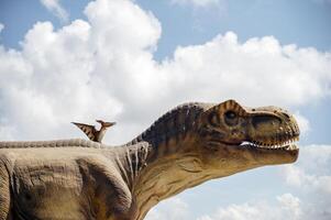 Artificial dinosaur tyrannosaurus, close-up of dinosaur head against sky background.Two dinosaurs. Pterodactyl and tyrannosaurus. One huge dinosaur and the other smaller. photo