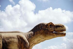 A huge tyrannosaurus dinosaur, a close-up of the dinosaur's head against the sky and clouds. With space for copying. The dinosaur in profile, you can see its teeth and huge mouth photo