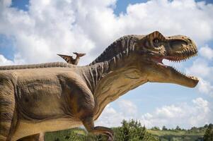 Two dinosaurs. Pterodactyl and tyrannosaurus. The huge dinosaur has its mouth open. Two dinosaurs against the sky and clouds. Copy space photo