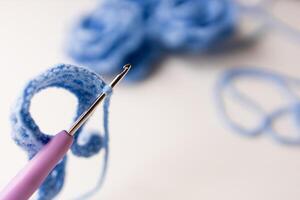 Close up of crochet hook with blue yarn loop in focus photo