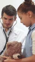 Compassionate doctor listens to a girl's teddy bear with a stethoscope video