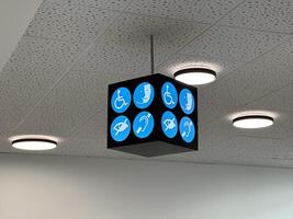 Nice, France - May 10, 2025 Accessibility sign hanging from ceiling, featuring various symbols for disabled services, illuminated by modern ceiling lights in a public building environment photo