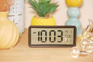 Digital clock displaying time and date on a wooden table photo