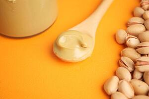 Pistachio butter spread on a spoon with nuts nearby photo