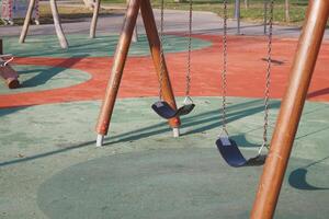 Empty swings at a colorful playground in sunny afternoon photo