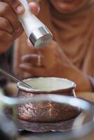Adding seasoning to a traditional dish in a cozy setting photo