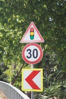 Traffic signs indicate speed limit and warning about curve photo