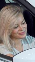 Gorgeous woman in a car, smiling while adjusting her hair in the side mirror video