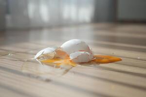 Egg shells and yolk spilled on wooden floor photo