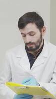 Bearded dentist attentively filling out medical documents while engaging with patient video