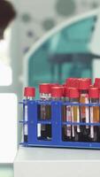 Vibrant blood samples in test tubes with a focused female medical worker analyzing data video