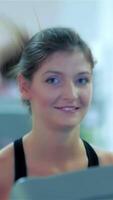 Joyful young girl running on a treadmill in the gym, smiling brightly at the camera video