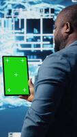Vertical African american expert holds tablet with isolated screen next to cloud computing systems, focused on AI brain development and machine learning for innovation. Smart tech data science. Camera A. video