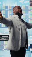 Vertical Black entrepreneur CEO speaking at a professional fintech convention, doing a business pitch on stage for the participants. With a powerful voice presenting infographics for success. Camera A. video